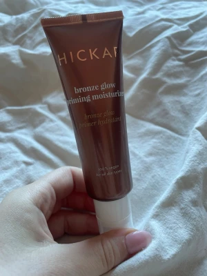 Hickap Bronze Glow Priming Moisturizer - Bronze Glow Priming Moisturizer från Hickap är en vegansk primer som ger huden en solkysst lyster. Tuben är bronsfärgad med vit kork och innehåller en återfuktande formula som passar alla hudtyper. Perfekt för dig som vill ha glow och en jämn bas. 50ml