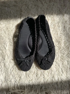 Svarta virkade ballerinaskor med rosett💓 - Snygga svarta ballerinaskor med virkad ovandel och söt rosettdetalj framtill. Skorna har rund tå och en mjuk innersula för extra komfort. Perfekta för dig som gillar en stilren och feminin look. Storlek 37 men passar mer än 38 då de är lite stora i storleken!💓