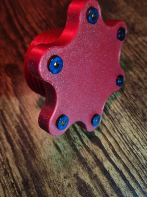 Röd 3D-printad stjärnformad adapter - Unik röd stjärnformad adapter i plast, 3D-printad med sex blå skruvar. Formen är sexuddig och adaptern har gängor på insidan. Perfekt för dig som gillar teknik eller DIY-projekt.