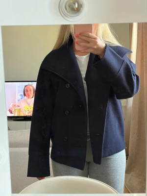 Mörkblå kappa - Säljer en mörkblå kappa med knappar framtill. Jackan har en klassisk, rak passform och är långärmad. Perfekt för dig som vill ha en stilren och tidlös look. Materialet känns kraftigt och varmt, idealiskt för kyligare dagar. Från GinaTricot, storlek 158/164 skulle säga xs/s. Den är nopprig men går säkert att ta bort om man försöker därav priset! 