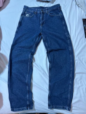 Blå raka jeans från Karl kani  - Säljer ett par klassiska blå jeans från Karl kani med rak passform och hög midja. Jeansen har fem fickor och Kappas logga broderad på myntfickan. Tillverkade i slitstark denim som ger en tidlös look.