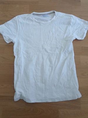 Vit t-shirt  - En basic vit t-shirt med rund halsringning och korta ärmar. Tillverkad i mjuk bomull, perfekt för en clean och enkel stil. Passar till allt och är ett måste i garderoben. Stryks innan den skickas till dig. Storlek S. Knappt använd och är nästan helt ny.