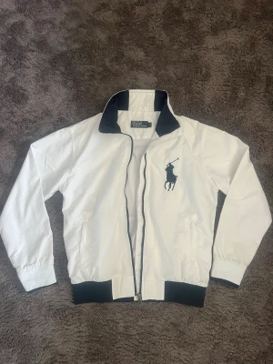  Polo Ralph Lauren vårjacka - Riktig fet och unik vårjacka från Ralph lauren. Har inte sett så många gå med denna. Den har några små lila fläckar vid kragen som man knappt lägger märke till. Perfekt för våren och lite kyligare sommar dagar 🤩.  Dma det är något du undrar över jag svarar så snabbt jag kan 😁