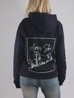 Marinblå hoodie med Apres Ski-tryck - Cool marinblå hoodie från Zenit med stor vit Apres Ski-illustration på ryggen och Zenit-tryck på bröstet. Hoodien har huva och en klassisk passform, perfekt för dig som gillar skidåkning och chill stil. Materialet ser ut att vara mjukt och bekvämt.