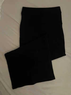 Svart långkjol i bomull från Gina - En stilren svart långkjol i mjukt bomullstyg. Kjolen har en rak och enkel design som gör den lätt att matcha med olika toppar och skor. Perfekt för dig som gillar minimalistisk stil och vill ha en bekväm kjol till vardags.