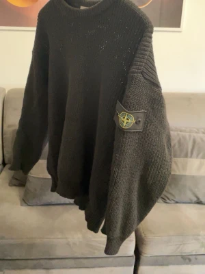 Svart stickad tröja Stone Island - Säljer en svart stickad tröja från Stone Island med klassisk patch på vänster ärm. Tröjan har grovstickad struktur, rund hals och långa ärmar. Perfekt för dig som gillar streetwear och vill ha något både snyggt och bekvämt. Passar bra till nästan allt och köptes för 4500kr. Den är knappt använd och är villig att sälja den för 650kr. Hör av dig om du vill diskutera pris eller ha fler bilder 