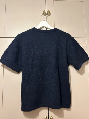 mörkblå stickad t-shirt - mörkblå stickad t-shirt med korta ärmar och rund halsringning. använd få tal gånger 