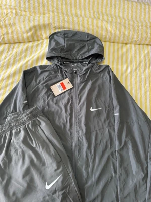 Nike Miller tracksuit - Hej jag säljer En fin lätt tränings tracksuit från Nike sportswear i modellen Miller i en fin ljusgrå färg perfekt för träning och att bara ha som en bekväm skön outfit den är helt ny faktiskt bara testats på men satt inte så bra som jag ville tyvärr 😊 XL fast passar L då den är liten i storleken