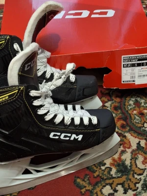 Svarta CCM junior hockeyskridskor st 38.5 - Säljer ett par svarta CCM hockeyskridskor med vita snören och detaljer i gult. Skridskorna har robust konstruktion, hög komfort och klassisk design med CCM-logga på sidan. Perfekta för isträning och matcher. St 38.5
