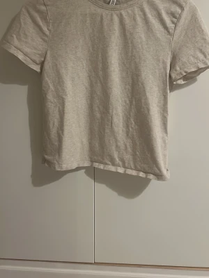 Beige t-shirt från H&M Divided - En enkel och stilren beige croppad t-shirt från H&M Divided. T-shirten har rund halsringning och korta ärmar. Perfekt basplagg att matcha med allt och tillverkad i mjuk bomull för skön känsla. Skriv till mig vid frågor 💕💕