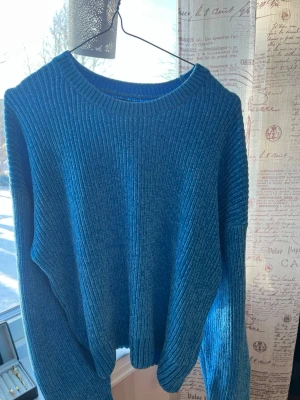 Blå ribbstickad tröja - Säljer en blå ribbstickad tröja med rund hals och långa ärmar. Tröjan har en avslappnad passform och är gjord i ett mjukt stickat material som känns skönt mot huden. Perfekt för att hålla sig varm under kyliga dagar.