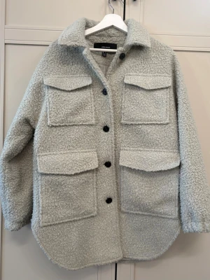 Ljusgrå teddycardigan från VERO MODA - Mysig ljusgrön cardiganjacka i teddy-material från Vero Moda. Jackan har fyra stora fickor framtill med lock, svarta knappar och en klassisk krage. Perfekt oversized look med rundad nederkant och lång ärm. Passar dig som gillar trendiga och bekväma plagg. Pris går att diskutera❣️