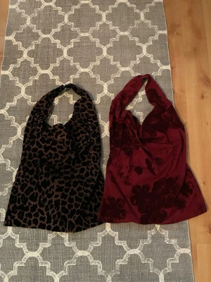 Två halterneck toppar i leopard & vinröd - Säljer två snygga halterneck toppar från Gina Tricot. Ena toppen är leopardmönstrad i bruna och svarta toner, den andra är vinröd med sammetsliknande blommönster. Båda är croppade och har knyt i ryggen. Perfekta för att lyfta din outfit!
