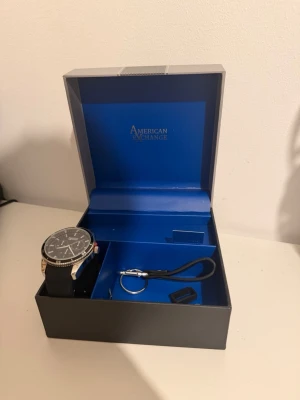 Armani exchange klocka - Säljer en silvrig Armani Exchange klocka med svart band, klockan har aldrig använts, endast prövats. Justerbar, unisex. Medföljer box och resterande paketering