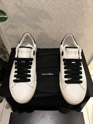 Dolce & Gabbana vita sneakers - Stilrena vita sneakers från Dolce & Gabbana med svarta detaljer och svarta skosnören. Skorna har låg profil, och är tillverkade i slätt läder. Skorna har använts max två veckor.