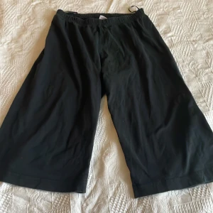 Svarta Star Wars pyjamasshorts - Säljer ett par svarta pyjamasshorts från Star Wars med bred resår i midjan. De har en avslappnad passform och är perfekta för att chilla hemma. Materialet känns mjukt och bekvämt mot huden. Perfekt för alla Star Wars-fans som vill ha något skönt att sova i.