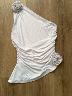 Bikbok One Shoulder topp med rynkningar och blomdetaljer - Bra skick! Använd några gånger men bra helhetsintryck 