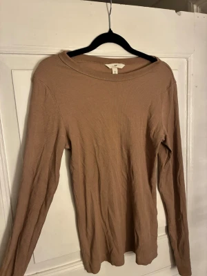 Beige ribbad långärmad topp H&M - Säljer en beige ribbad långärmad topp från H&M. Toppen har en enkel och clean design med rund halsringning och är tillverkad i mjuk bomullsmix. Perfekt att styla med jeans eller kjol för en chill look. Passar S/M.