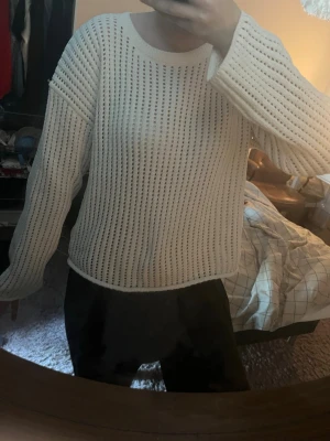 Vit stickad tröja med hålmönster - Säljer en vit stickad tröja med hålmönster och rund hals. Tröjan har långa ärmar och en avslappnad passform. Perfekt för lager på lager och ger en chill vibe till din outfit.