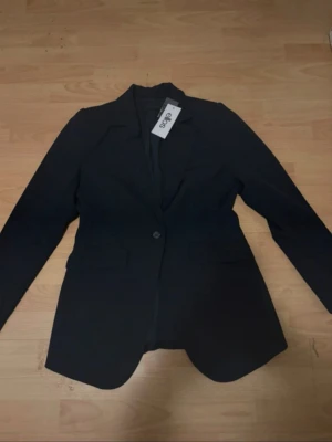 Figursydd kavaj strl 36 - Märke: Ellos Storlek: 36 Färg: Navy Skick: Ny med prislapp Nypris: 699 kr Modellnamn hos Ellos: Ellos Collection - Slim Fit Kavaj  PM vid intresse av mer bilder. 