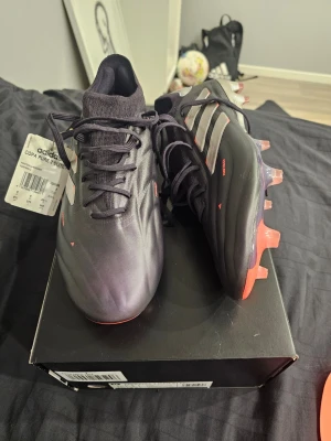 Adidas Copa Pure 2 Elite FG fotbollsskor - Snygga Adidas Copa Pure 2 Elite FG fotbollsskor i färgen Aurora med silvriga stripes och röda detaljer. Skorna har en strömlinjeformad design, snörning och FG-dobbar för spel på naturgräs, men funkar utmärkt som AG (konstgjord gräs). Tillverkade i syntetmaterial och läder för bästa känsla och kontroll på planen. Kostar ordinarie pris 2699. Och fick till min födelsedag i januari. Tyvärr för stor i passform och säljer. Hör gärna av er vid frågor, pris kan diskuteras.
