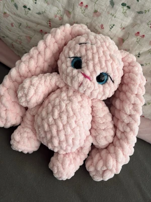 Rosa virkad kanin med långa öron - Supermjuk och fluffig rosa kanin i virkat garn med stora blå ögon och långa öron. Kaninen har broderad nos och mun i rosa och svart, och är perfekt som gosedjur eller dekoration. Materialet är tjockt, mjukt garn som ger en mysig känsla. 25 cm