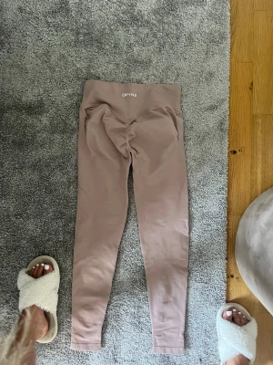 Beige  leggings från Dfyne  - Säljer ett par beige leggings från DFYNE med hög midja och scrunch-detalj bak. De är stretchiga och sitter tight, perfekta för träning eller chill. Materialet känns mjukt och följsamt mot kroppen. Snygg och enkel design utan synliga sömmar. 