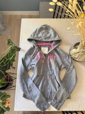 Grå zip hoodie från Hollister - Snygg grå hoodie från Hollister med dragkedja och huva. 