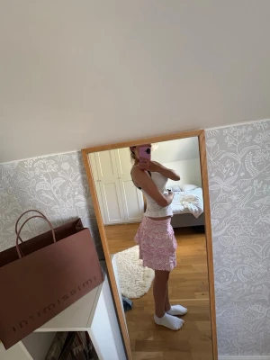 Rosa volangkjol med spetsdetaljer - Supersöt rosa kortkjol med volanger och spetsdetaljer. Kjolen har en feminin look och är perfekt för dig som gillar romantisk stil. Materialet känns lätt och luftigt, perfekt för varmare dagar.
