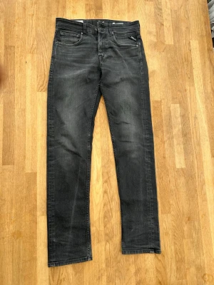 Svarta jeans från Replay - Säljer ett par svarta jeans från Replay med diskret tvättad look och raka ben. Klassisk femficksmodell med Replay-logga på bakfickan. Jeansen har normal midja och är tillverkade i bomull med lite stretch för extra komfort. W28 L32
