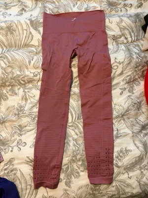 Rosa seamless leggings från Gymshark - Säljer ett par rosa seamless leggings från Gymshark i storlek XS. De har hög midja, ribbade detaljer längs benen och ventilerande meshpartier. Perfekta för träning eller chill. Materialet är stretchigt och andas bra.