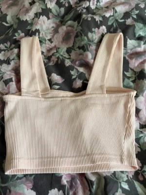 Beige ribbad linnetopp - Snygg  ribbad linnetopp med breda axelband. Toppen är croppad och har en enkel, stilren design som passar perfekt till jeans eller kjol.