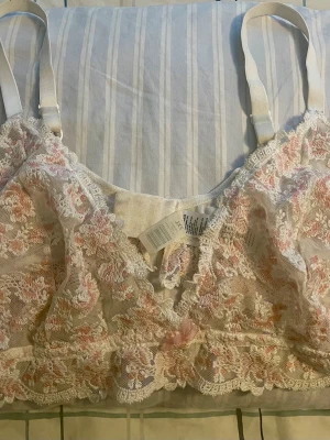 ” U Sophie triangle” Bralette i stl 2xl fr Cubus  - Rosa/Vit. Provad/använd enstaka gång. Uppskattar att den sitter bäst på 90-100 F/G.  Bralette i romantisk broderie anglaise med blommotiv. Bh:n är bygellös, har justerbara axelband och stängs med hyskor bak.  