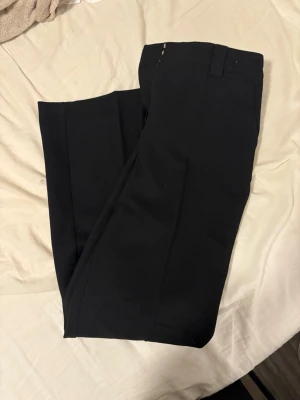 Svarta raka kostymbyxor i twill - Snygga svarta kostymbyxor från H&M i twill med raka ben och mellanhög midja. Klassisk passform med hällor för bälte och diskreta fickor. Perfekta för en stilren look och lätta att matcha med både skjorta och t-shirt.