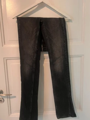 Svarta jeans med slits från Zara - Snygga svarta jeans från Zara med raka ben och slits nertill. Jeansen har klassisk femficksdesign, knapp och dragkedja framtill samt kontrastsömmar. Tillverkade i denim med en cool tvättad look.