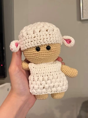 Handvirkad amigurumi  - Söt handvirkad docka med beige kropp och vit fårdräkt. Dockan har svarta pärlögon och en fårmössa med vita öron. Pris är för material+arbetstid