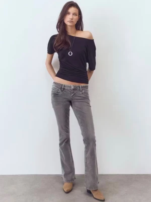 Grå bootcut jeans med låg midja - Säljer ett par grå bootcut jeans med låg midja och klassiska femficksdetaljer. Jeansen har en snygg tvättad look och vida ben nertill. Perfekta för dig som gillar retrostil och vill ha ett par bekväma jeans med cool attityd.