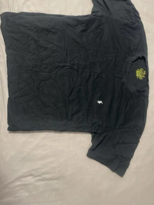 Svart t-shirt från Ralph Lauren - Svart t-shirt från Ralph Lauren med klassisk passform och liten vit broderad logga på bröstet. Tillverkad i 100% bomull och har korta ärmar. Perfekt basic-plagg med stilren look.