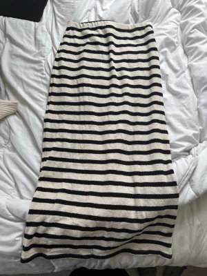 Randig kjol från Gina Tricot - Säljer en lång kjol från Gina Tricot med svartvita horisontella ränder. Kjolen har en rak passform och är gjord i ett mjukt, stickat material som känns skönt mot huden. Perfekt för en avslappnad och trendig look.