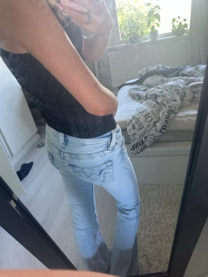 Ljusblå bootcut jeans - Säljer ett par ljusblå bootcut jeans med låg midja och klassiska fem fickor. Jeansen har en snygg tvätt och är tillverkade i denim med lite stretch för skön passform. Perfekta till en avslappnad och trendig look.