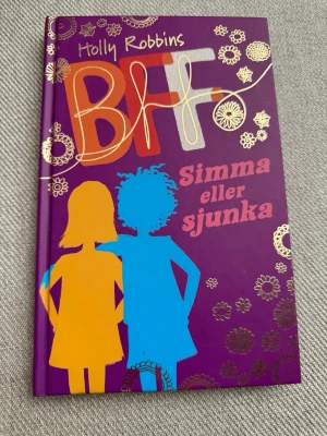 BFF: Simma eller sjunka - Färgstark ungdomsbok med lila hård pärm, dekorerad med guldmönster och siluetter i orange och blått. Titeln 'BFF: Simma eller sjunka' handlar om vänskap, skola och att hitta sin plats. Perfekt för dig som gillar berättelser om vänskap och tonårsliv.