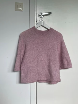 Ljusrosa/lila stickad tröja med halvlång ärm - Stickad tröja med alpacka inblandning. Gott skick, lite nopprig som dock kan tas bort med noppborttagare. Pris kan diskuteras!