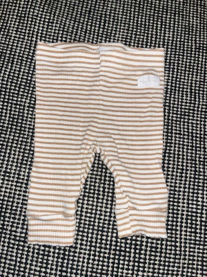 Randiga leggings från Sinsay Baby - Supersöta ribbade leggings från Sinsay Baby i beige och vitt med tunna horisontella ränder. Mjukt och stretchigt material som passar perfekt för små barn. Elastisk midja för extra komfort och enkel påklädning.