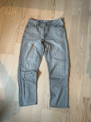 Grå jeans från Jack & Jones  - Säljer ett par grå jeans från Jack & Jones med klassisk femficksdesign och raka ben. Jeansen har knapp- och dragkedjeförslutning samt detaljerade sömmar. Materialet är denim och färgen är ljusgrå, perfekt för en avslappnad och cool look.