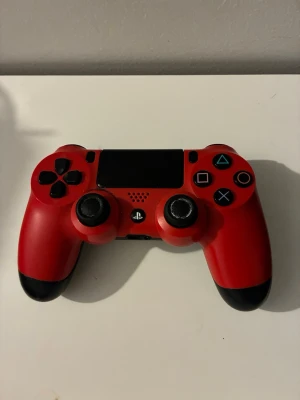 Röd och svart PS4 DualShock 4 kontroll - Snygg röd och svart DualShock 4 handkontroll till PlayStation 4 från Sony. Kontrollern har klassisk layout med touchpad, två analoga spakar, styrkors och ikoniska PlayStation-knappar. Kan förekomma stikdrift. 