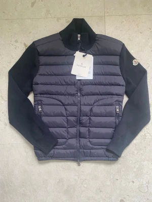 Moncler Tricot cardigan - Hej! Nu säljer jag denna riktigt snygga och stilrena Moncler-cardigan. Den är helt ny och i storlek M, men passar som en Small eller en liten Medium.  Digitalt kvitto finns, och både loggan samt QR-koden går att skanna.  Nypris: cirka 10 000 kr Mitt pris: 2 799 kr  Tveka inte att höra av dig om du har några frågor eller funderingar.  Priset är inte hugget i sten.  Mvh, Agge