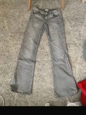 Grå bootcut jeans med låg midja - Snygga grå jeans med bootcut passform och låg midja. Klassisk femficksmodell med knappgylf och ljus tvätt. Perfekta för en avslappnad och trendig look. Kan lägga upp bilder med jeansen på!