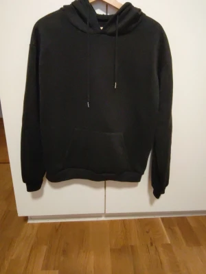 Svart hoodie med tryck Intense Feelings - Svart hoodie med huva och dragsnören. På ryggen finns ett stort grafiskt tryck i rosa och vitt med texten 'Intense Feelings' och en staty-inspirerad design. Klassisk känguruficka framtill. Perfekt för dig som gillar streetwear och coola prints. Knappast använd , för liten köpt för 160 kr egentligen. 