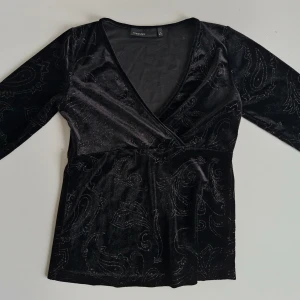 Svart omlottopp i sammet KappAhl - Trendig sammetstopp från KappAhl 🖤  V-ringad med trekvartsärm och glittrigt mönster 🌸 Sparsamt använd, i fint skick! Storlek S-M  Pris är självklart förhandlingsbart :) Hör gärna av er vid frågor och glöm inte att kolla in garderoben för fler liknande plagg, bundlerabatt finns! 💕