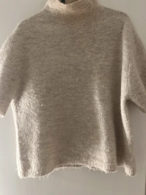 Beige stickad tröja med polokrage - Beige stickad tröja från Gina tricot med korta ärmar och hög polokrage. Storlek xs. 